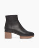 Side view of the Nigella Clog in Deep Sea. Set on a solid wood heel and platform, the midsole is rounded and completely unique, with a simple, clean bootie silhoute. Side tab. Inside-zip closure. 1