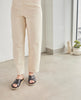 Model wearing a low pine wedge slide sandal with rubber sole and intertwined leather tube straps across foot. 5