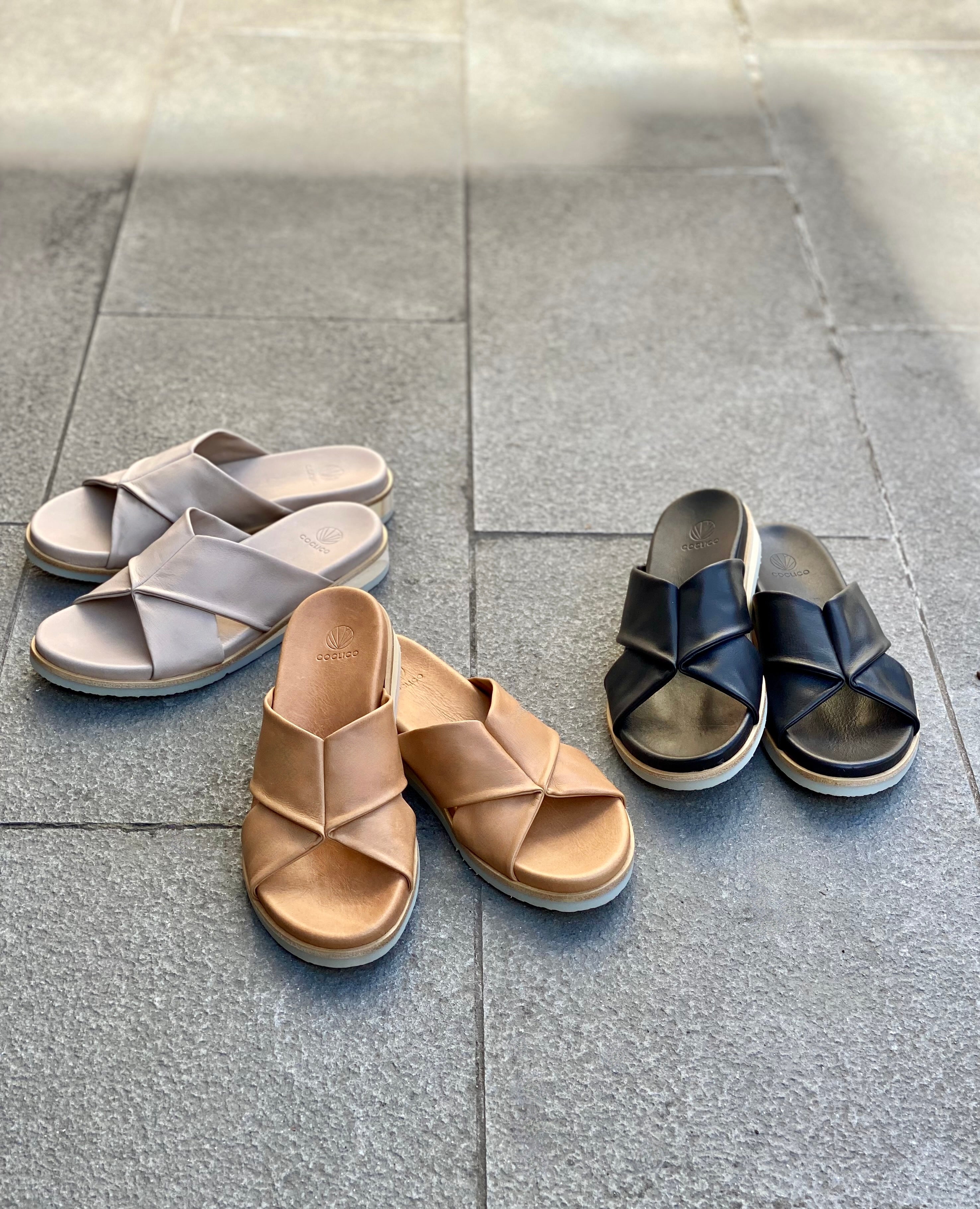 Coclico Pasque Sandal in Black, Greige and Mandorla leather displayed on tile flooring.