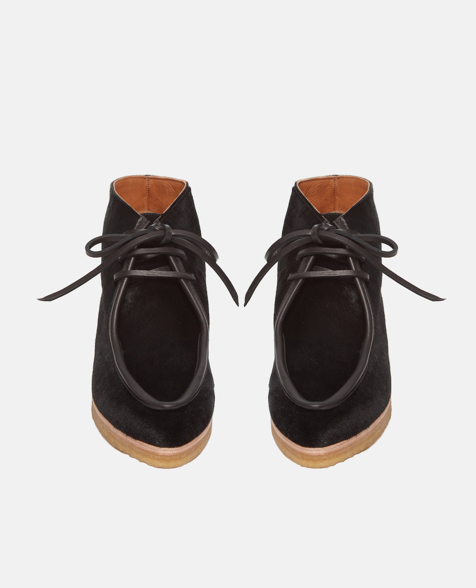 Front view of the Coclico Quinn Boot sophisticated chukka bootie in our limited edition black lux hair. Gentilly pointed moc toe, raised black leather piping and lace closure. Inside you'll discover a 30MM hidden wedge that adds height and comfort.