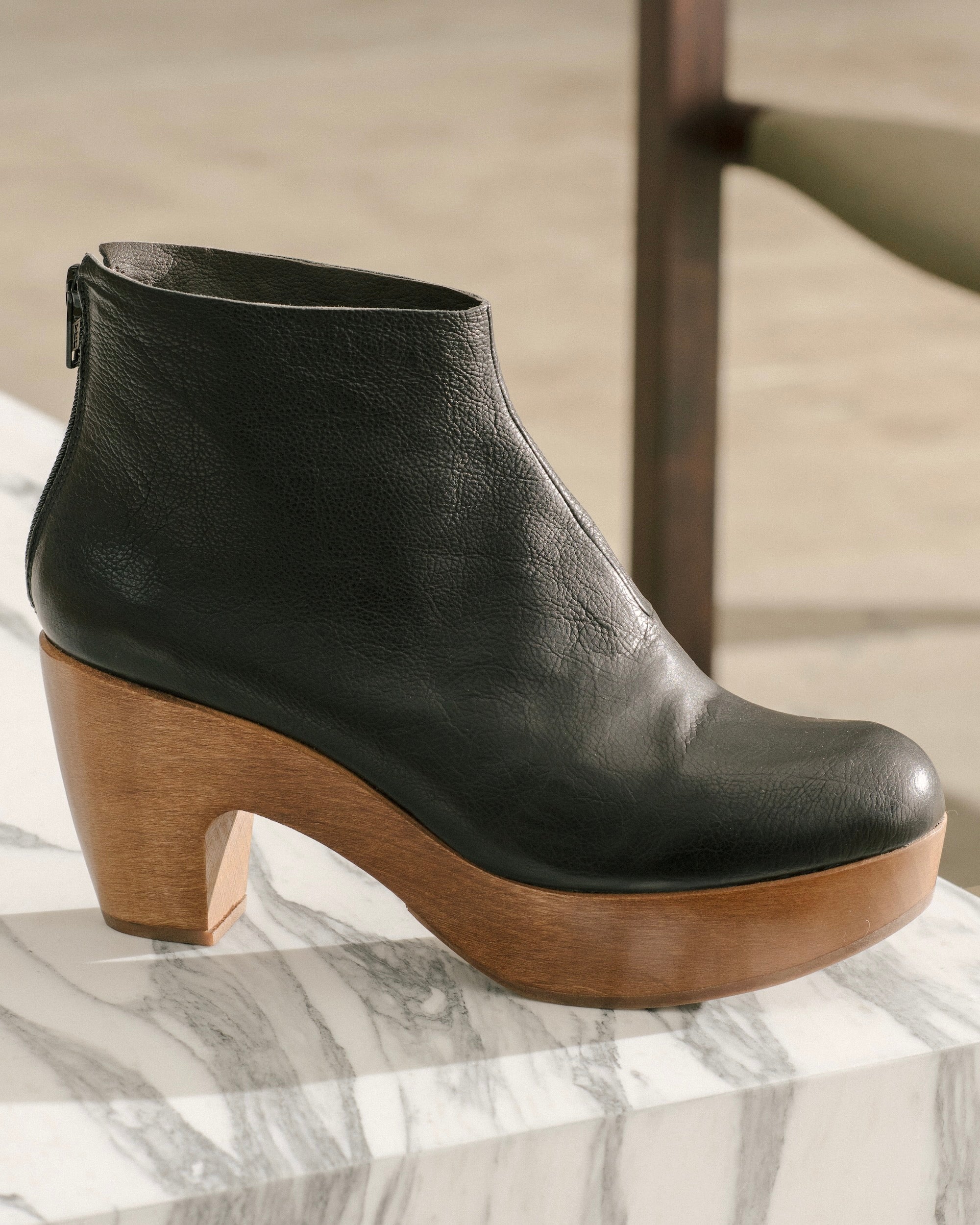 Side angled view of the Coclico Tik Clog in Black placed on a marble table.