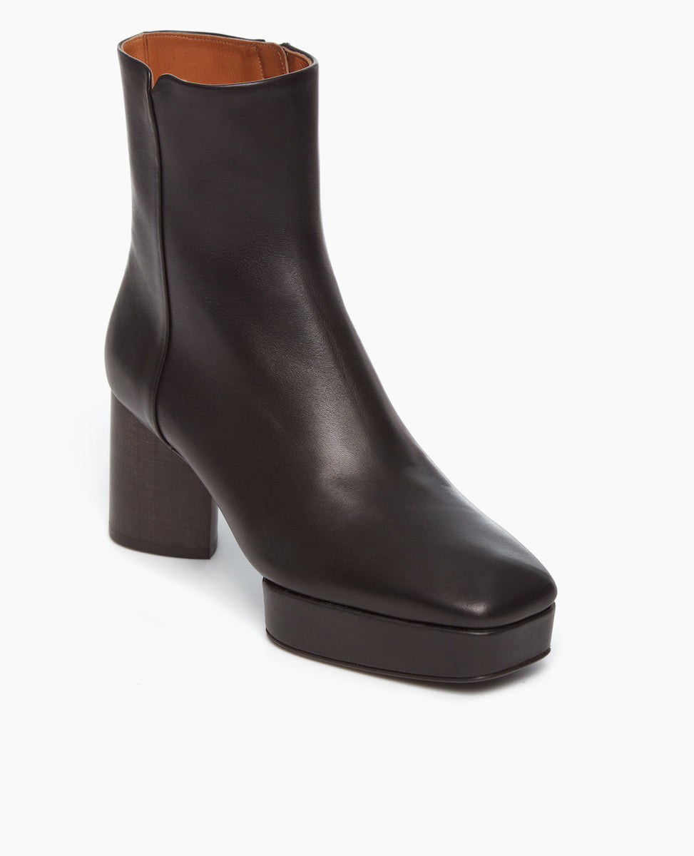 Angled view of the Travis Boot in Black: features a formed squared toe and balanced with a platform. Inside zip closure.