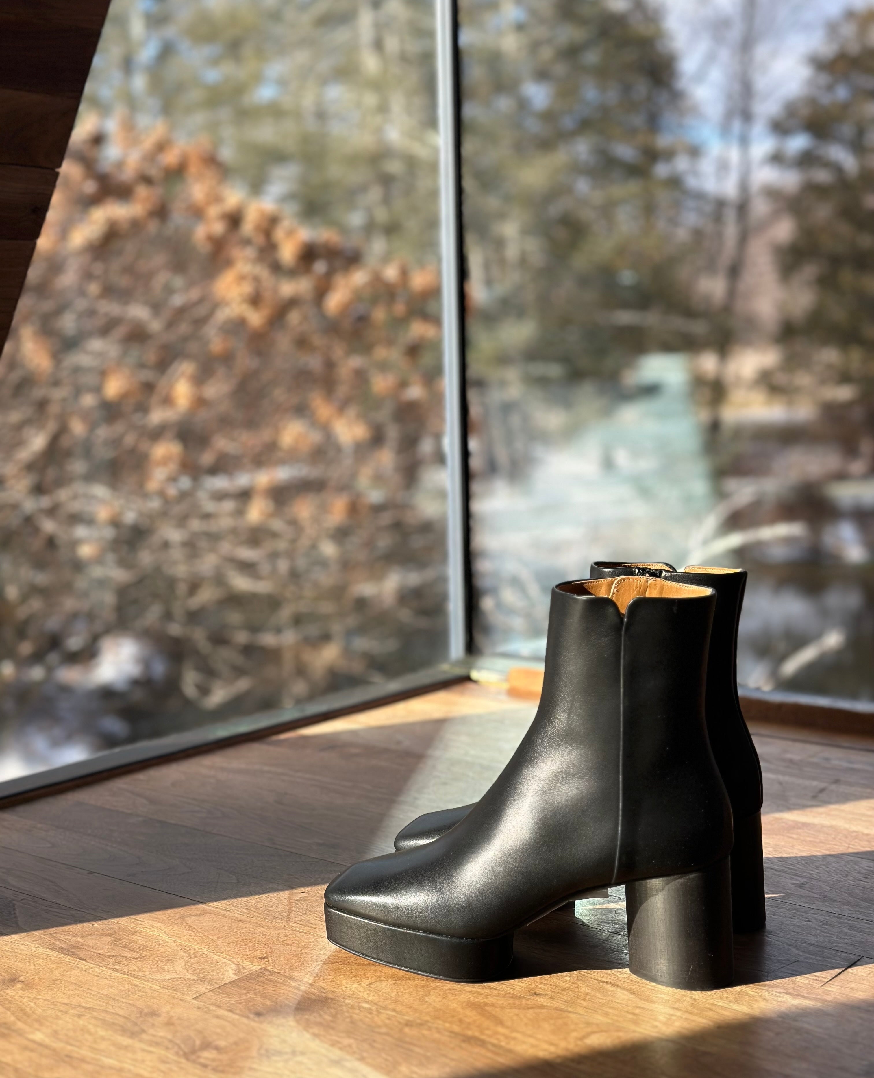 View of the Travis Boot in Black facing glass with nature pictured in the background.