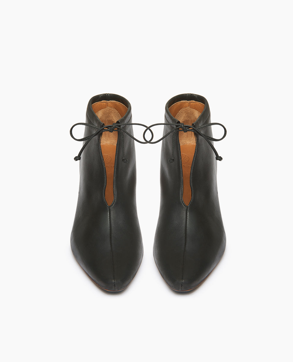 Front view of the Waffles Bootie in Black Leather; featuring a softly arched solid wood heel and gathered tie at the ankle revealing just enough to be both feminine and practical.