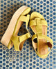 Close up of Coclico Ally Clog in Certosa suede: an open t-strap sandal on solid wood wedge platform with velcro closure on blue tiled flooring. 4