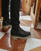 Side view: Coclico Cappucho Boots in Black leather, a slip-on chelsea boot with water-resistant treated soles and a mid-height EVA sole platform - red & white marble flooring. 4