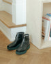 Pair of Black leather Shearling boots with weather-conscious leather, upper zipper closure, shearling lining, padded edge, angular toe and a green mid-height EVA sole placed near staircase.  7