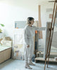 Artist modeling the Coclico Furin Boot in Latte nubuck: a mid-calf height boot with front zipper closure, leather pull tab, scored rubber sole and a mid-height solid wood block heel - in art studio. 4