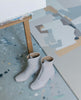 Pair of Coclico Furin Boot in Latte nubuck next to art work. 3