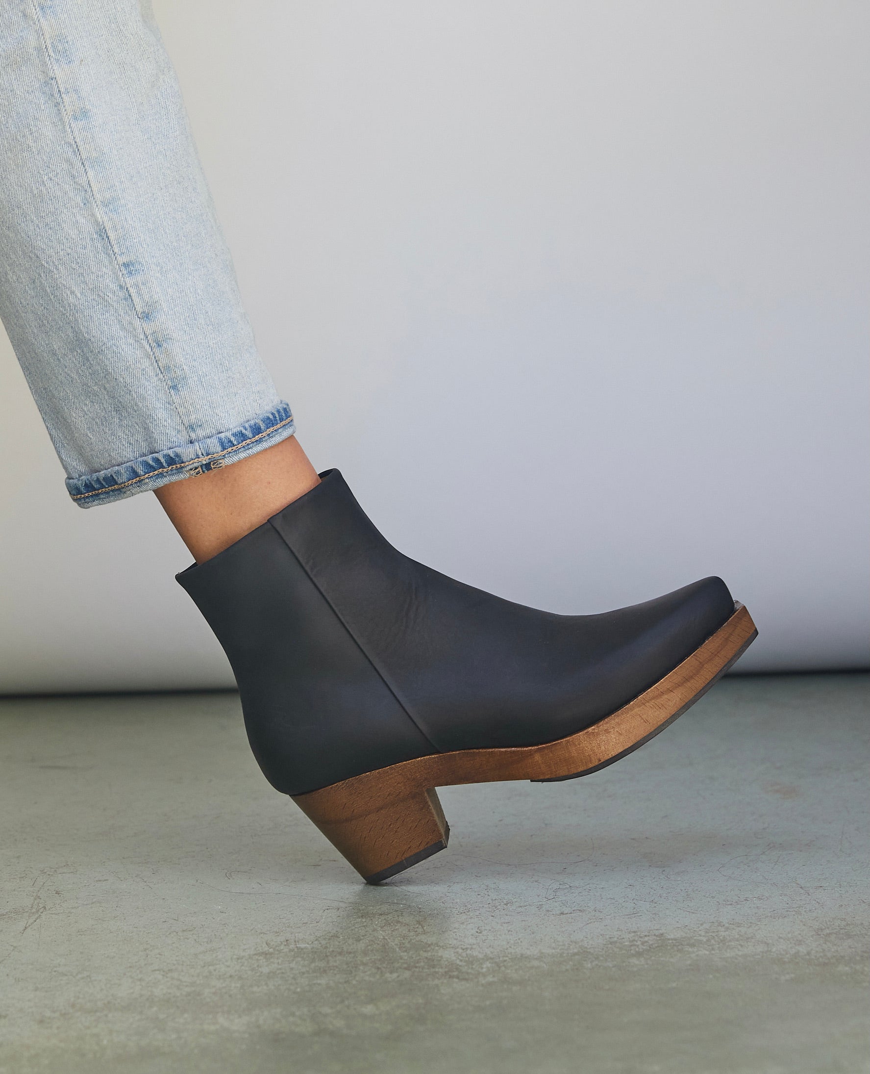 Women's lower right leg pictured wearing light jeans with the Kabuki Clog in Black.