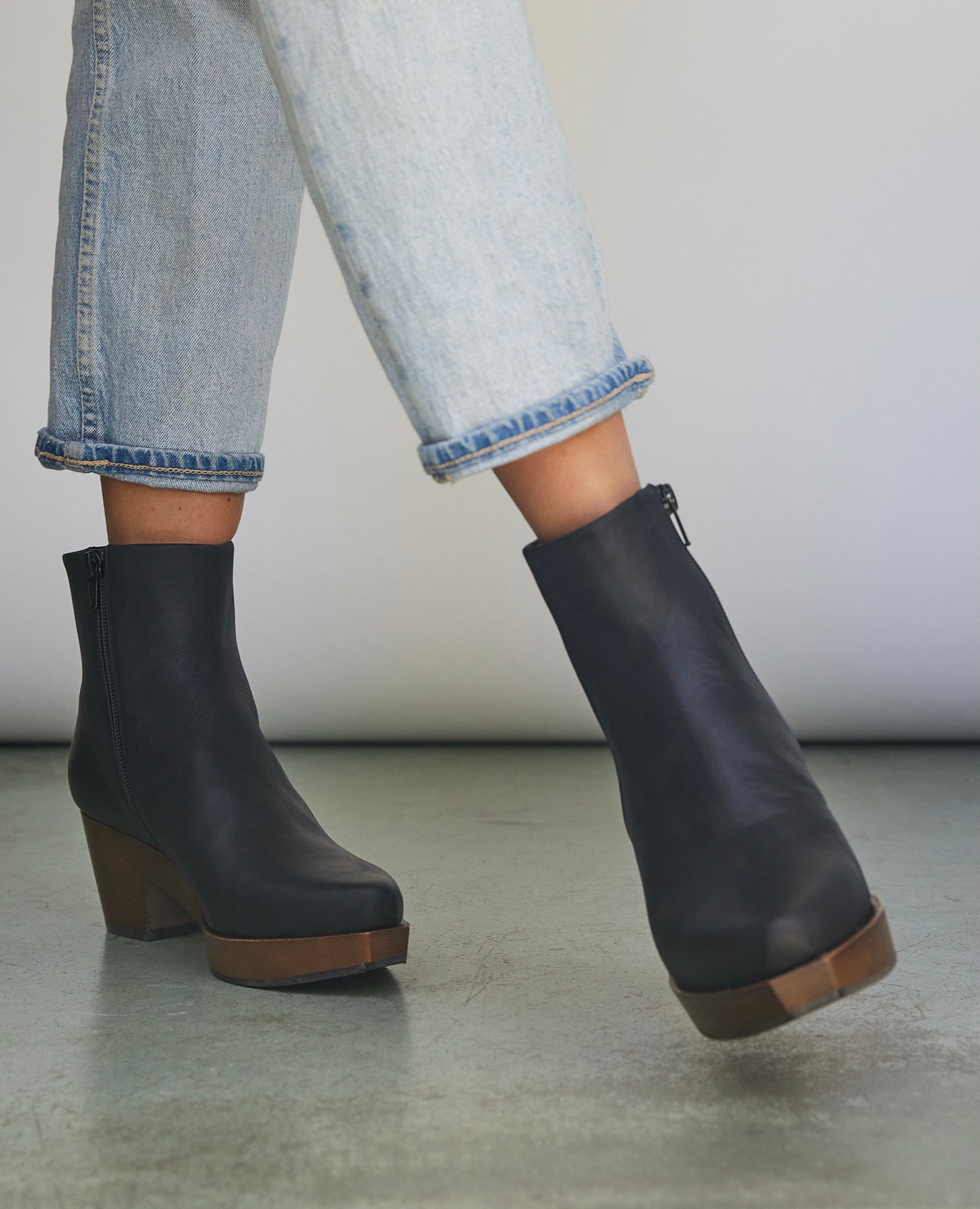 Women's legs in light jeans wearing the Kabuki Clog in Black leather.