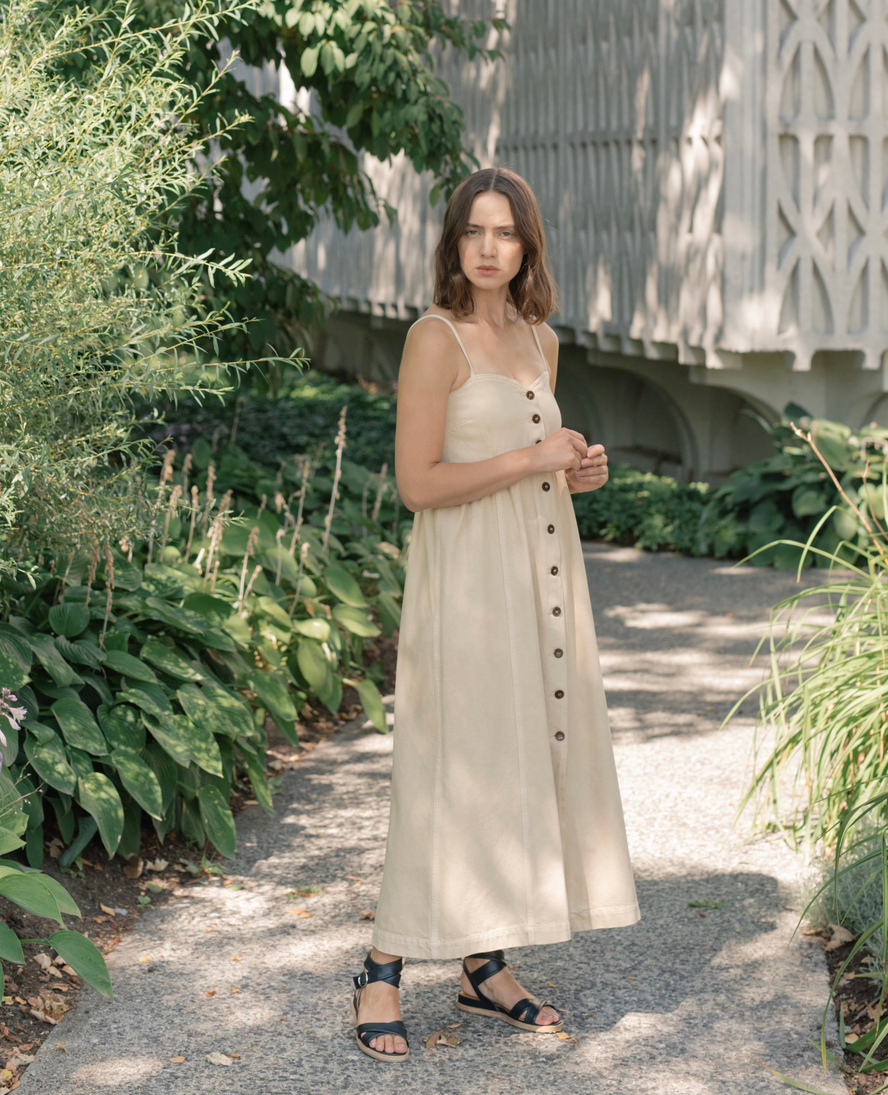 Woman modeling Coclico Katriane Sandal in Deep Sea leather: open sandal with tubular straps across foot and ankle, buckle closure, slight leather wrapped wedge.