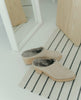 Coclico Kera Shearling Clog in Latte nubuck, a slip-on mule with a mid-height wood block base, tapered toe, shearling lining - top view shot of mules on carpet. 2