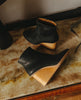Top, side view of a solid-wood, sculpted, inset 75mm height wedge with inside zip closure, seam detail on top of foot and rounded toe - placed on marble table. 3
