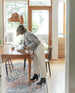 Woman leaning over table modeling the Coclico Lono Boot in Prismanet Black leather.  5