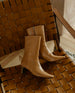 Pair of Coclico Wakame Boot in Mandorla leather on leather woven chair. 3