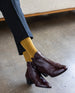 Woman's feet wearing yellow socks with the Calm Boot in cordovan classic. 4