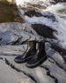 Pair of the France Boot in Black Leather placed outside on a rock with a lake pictured behind.  4