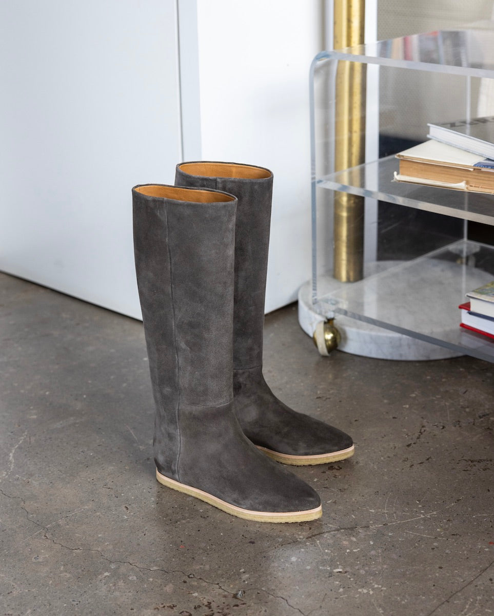 Coclico Quest Boot in Anthracite placed on a concrete floor with acrylic shelves in the back.