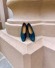 The Coclico Haloumi Flat in Deep Sea leather placed on terracotta pillar, top view. 4