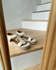 Coclico Ally Clog in Greige leather: Open t-strap sandal on a wood wedge platform with velcro closure displayed on wooden steps. 5