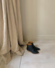 Top view of Java Boot in Black placed on white flooring with a curtain to the left of the pair. 5