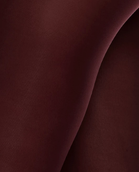A close-up view of a smooth, dark burgundy fabric with a soft, matte texture and a slightly curved surface.