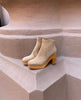 A modern, minimalist clog with a 3.5 inch solid wood heel, angled topline and back zip closure place on a large terracotta pillar. 5