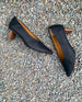 Close up, top view of a seasonless Coclico slip-on heel with a choked throat line, pointed toe, scultped oval shaped solid wood heel and subtle stichwork - on gravel. 8