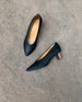 Top, side view of the Coclico Wumo Heel in Black/Coabi leather on concrete flooring. 4