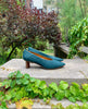 Side view: Coclico Wumo Heel in Bottle suede - with greenery in background. 7