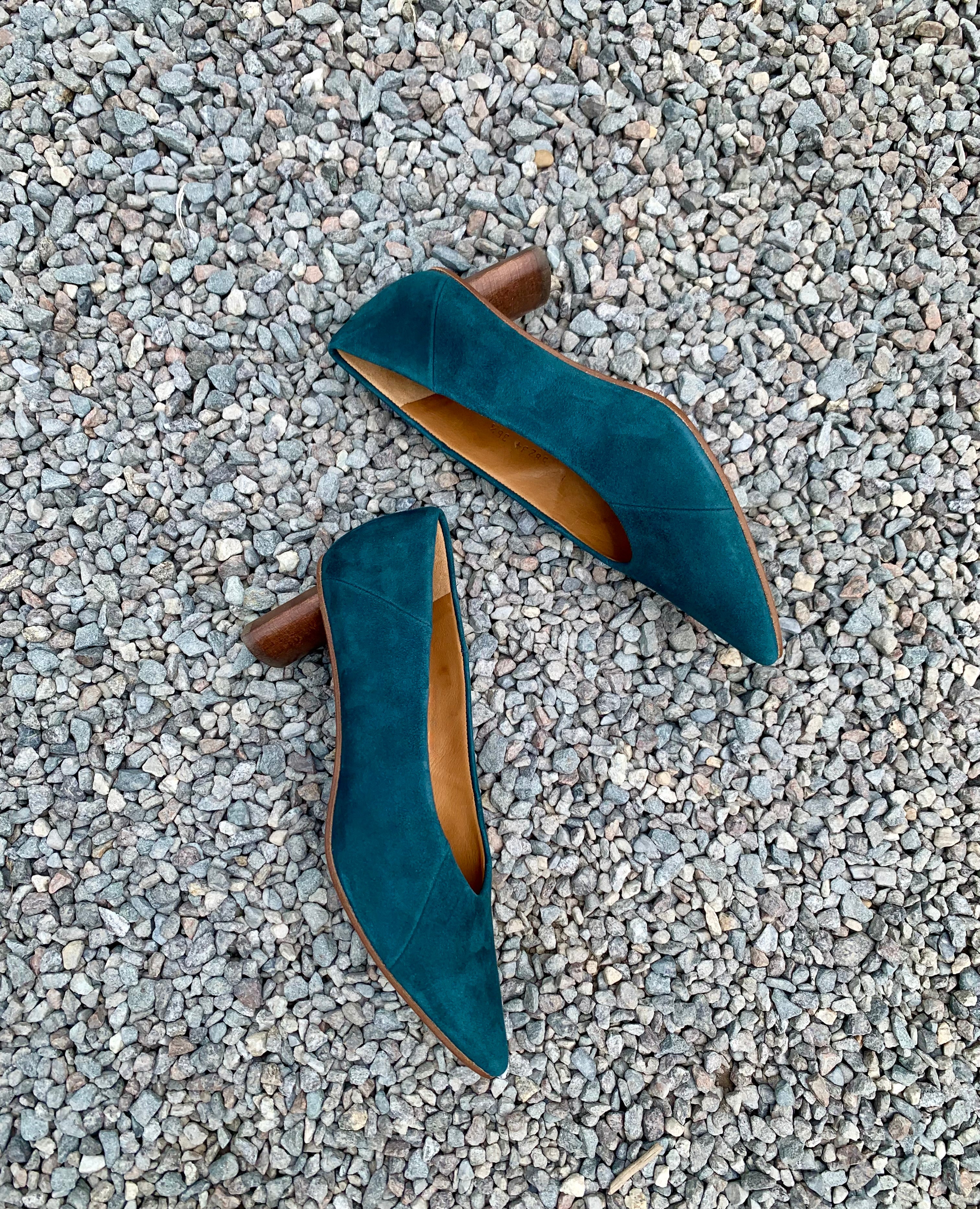 Top view of a seasonless Coclico slip-on heel with a choked throat line, subtle stichwork and a scultped, oval shaped solid wood heel with a hand-painted chestnut finish - on gravel.