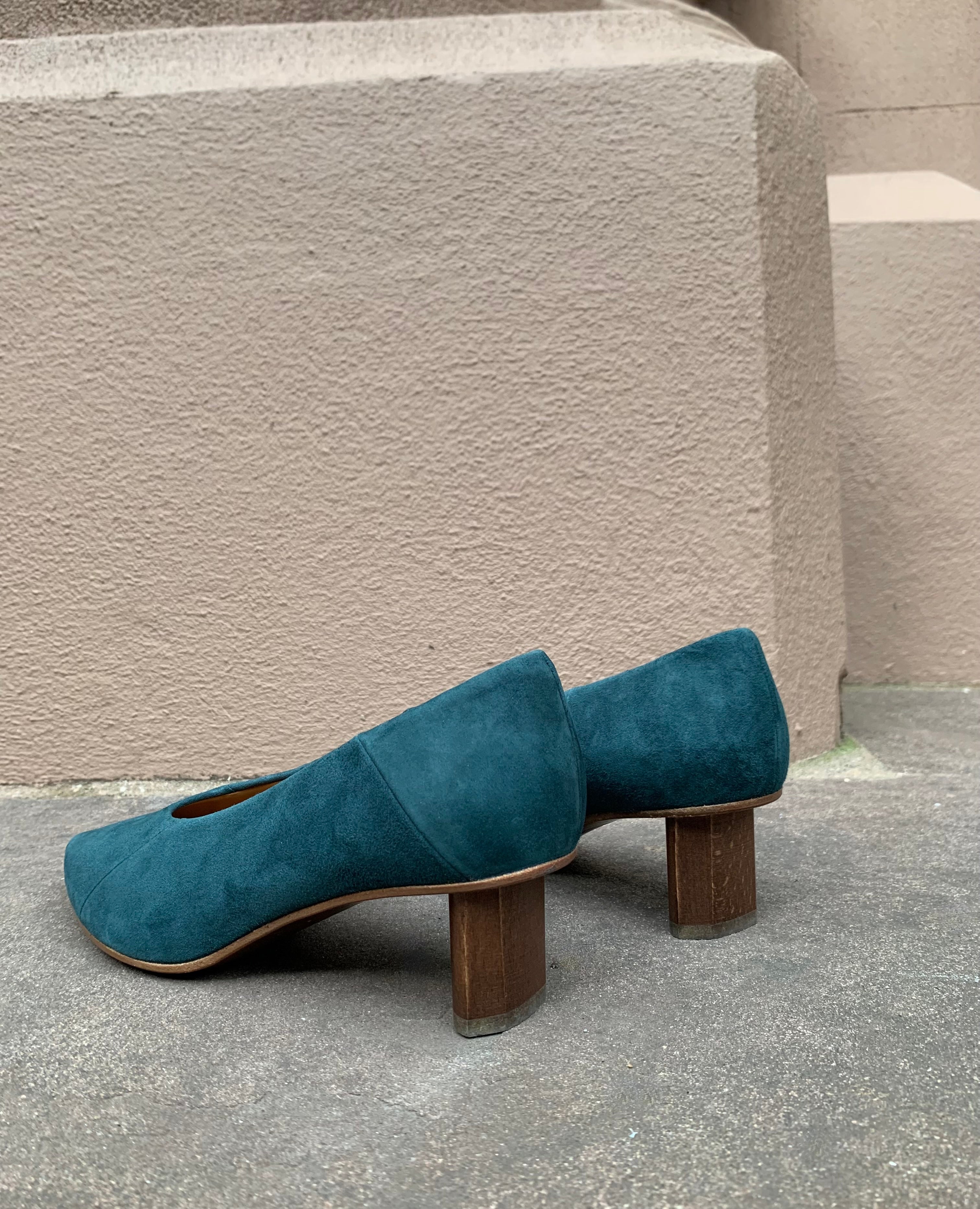 Cose up of the Coclico Wumo Heel in Bottle suede featuring the oval shaped solid wood heel with a hand-painted chestnut finish.