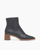 Side view: Coclico Juju Boot in Deep Sea (blue/black) leather: a minimalist boot featuring an inside zip closure, soft squared-off toe, mid-height solid wood block heel, mid-height shaft. 1