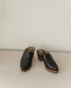 Front view of the Kera Shearling Clog placed on a wooden ground with a white backdrop. 7