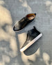 Top view of the Oro Sneaker in Black with the left lying on its side against cement flooring.  4