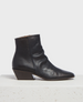 A sleek black leather ankle boot with a pointed toe, featuring a textured surface, a side zipper, and a distinctive angled wooden block heel. 1