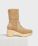 A tan suede mid-calf boot with a rounded toe, featuring a chunky wooden heel and a soft, plush lining visible at the top. 2