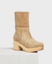 A tan suede boot with a mid-calf height, featuring a rounded toe, a chunky wooden heel, and a soft, plush lining. 1