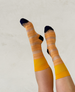 Knee-high socks featuring alternating bands of sheer beige mesh and textured orange knit, with solid yellow cuffs and dark blue toes and heels. 1