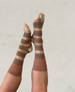 Knee-high socks featuring alternating horizontal stripes of beige and brown with intricate patterns, a ribbed texture at the top, and a smooth, seamless finish at the toes and heels. 2