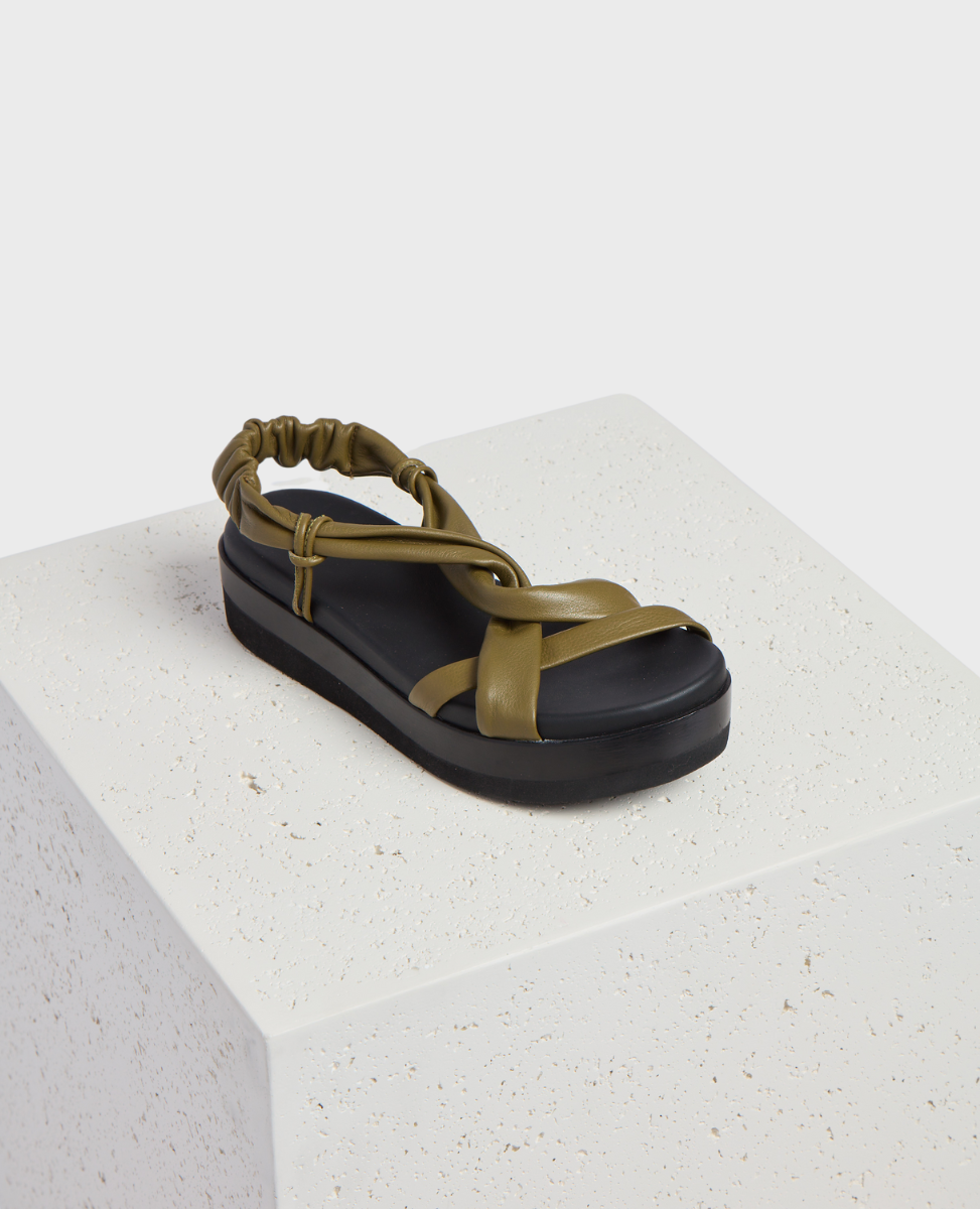 A sandal with an olive green, twisted strap design and a black, cushioned sole, featuring an elasticized back strap for a secure fit.