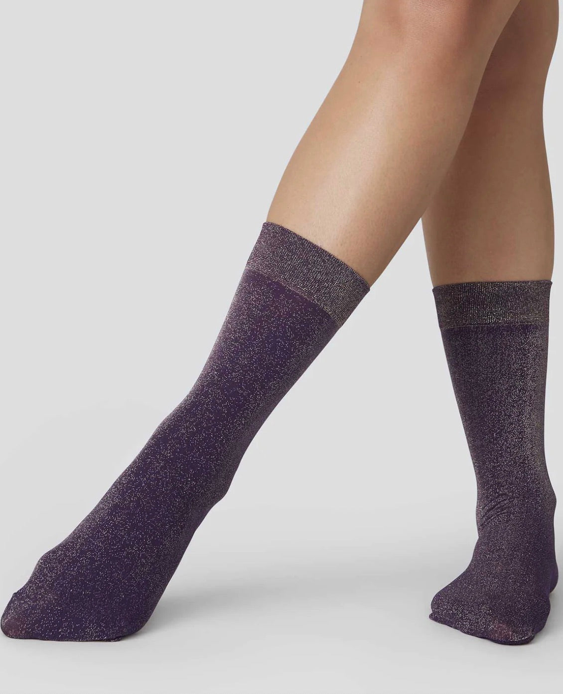 Shimmery socks shown on a woman's legs while they are crossed.