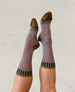 A pair of mid-calf socks featuring a light brown base with a circular pattern, dark brown toe and heel accents, and a striped black and brown cuff. 1