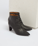 A pair of sleek, black leather ankle boots with pointed toes, a smooth texture, and medium-height block heels, featuring a subtle side zipper for closure. 2