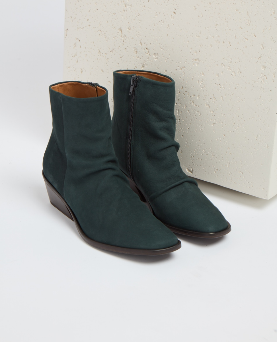 Dark green ankle boots with a smooth suede texture, featuring a side zipper and a low wedge heel, crafted from leather with a sleek, minimalist design.