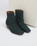 Dark green ankle boots with a smooth suede texture, featuring a side zipper and a low wedge heel, crafted from leather with a sleek, minimalist design. 2