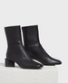 Sleek black leather ankle boots with a smooth texture, featuring a rounded toe, side zipper, and a sturdy block heel. 1