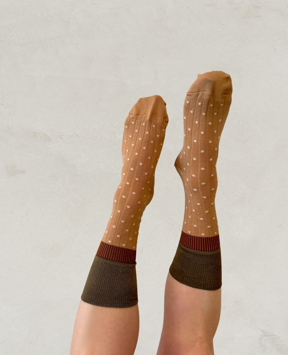 A pair of brown socks with white polka dots and contrasting dark brown ribbed cuffs, featuring a soft, knitted texture and a snug fit.