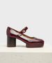 A glossy, dark burgundy Mary Jane shoe with a chunky block heel, rounded toe, and a single strap across the instep, featuring a smooth, polished leather finish. 1